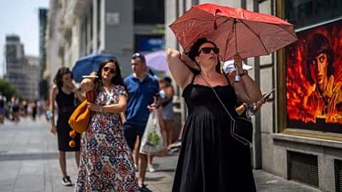  A woman holds an umbrella to shelter from the sun during a hot sunny day in Madrid, Spain, Monday, July 18, 2022.