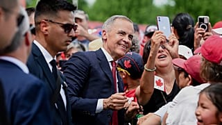 Canada's Prime Minister Mark Carney takes a selfie with a spectator following mid-day Canada Day celebrations at LeBreton Flats in Ottawa
