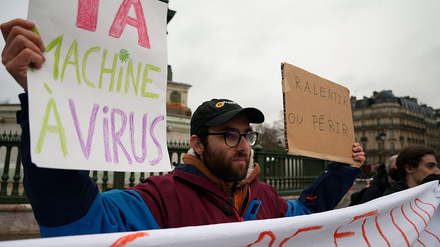 Des manifestants brandissent des banderoles lors d'un rassemblement place de la Bastille à Paris, lundi 10 février 2025, avec slogans "ralentir ou périr" et "machine virus IA".