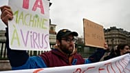 Demonstrators hold up banners and during a protest on Paris' Bastille Square, Monday, Feb. 10, 2025. Signs in French read "slow down or perish" and "AI virus machine". 