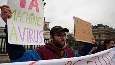 Manifestantes exibem faixas durante protesto na Praça da Bastilha, em Paris, em 10 fevereiro 2025. Mensagens em francês: “abrandar ou perecer” e “máquina de vírus da IA”.