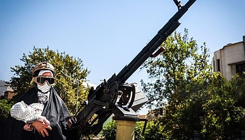 A woman holding a baby behind a machine gun" Photo: Mostafa Tehrani / Tasnim News Agency