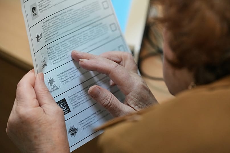 A voter looks through a ballot during the parliamentary election in Moscow, 20 September, 2026