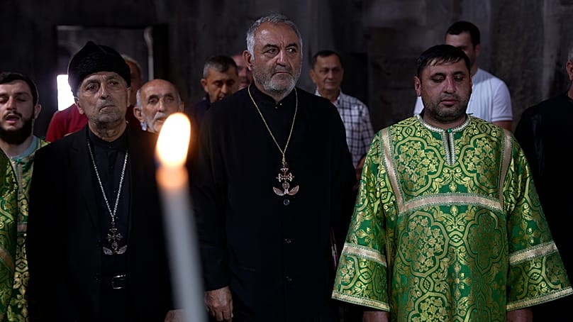 Community leaders and clergy stand during service in black clerical clothing wearing distinctive cross necklaces, Gandzasar, 21 September 2026