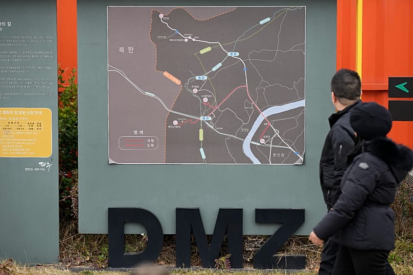Visitors walk past near a map of the Demilitarised Zone (DMZ) at the Imjingak Pavilion in Paju, 22 November, 2023
