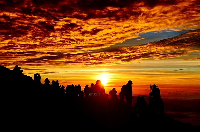 Los escaladores observan el amanecer desde la cima del monte Fuji