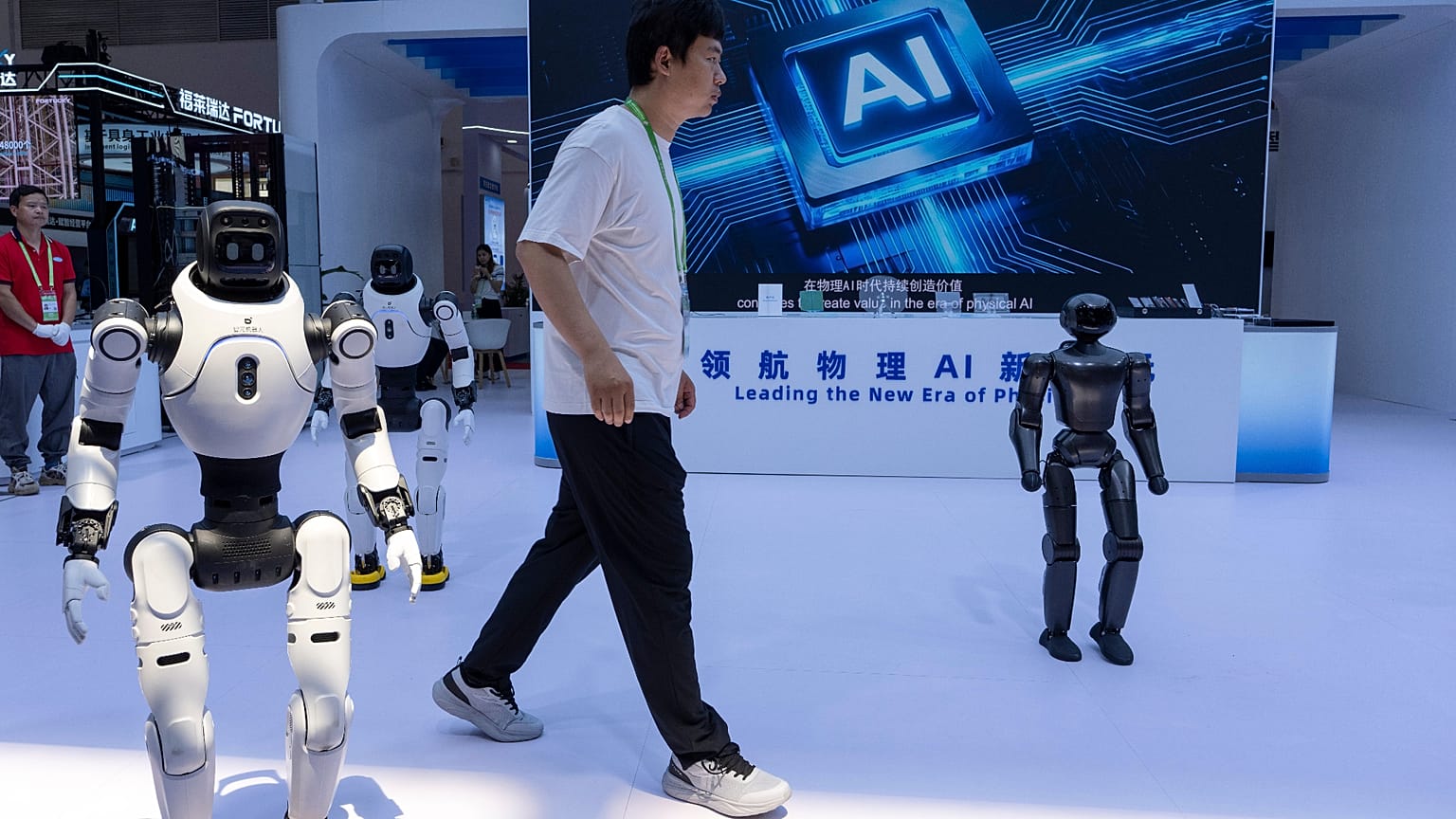 A worker passes by robots from Chinese company Lens at the China International Supply Chain Expo in Beijing 