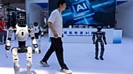 A worker passes by robots from Chinese company Lens at the China International Supply Chain Expo in Beijing 