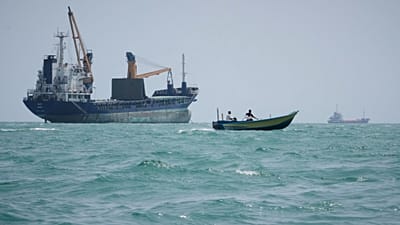 یک قایق موتوری از کنار یک کشتی باری عمومی که در تنگه هرمز، در نزدیکی بندرعباس ایران لنگر انداخته است، عبور می‌کند؛ یکشنبه، ۶ سپتامبر ۲۰۲۶