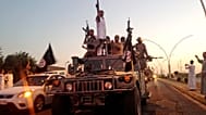 des combattants du groupe "État islamique" défilent à bord d'un véhicule blindé réquisitionné aux forces de sécurité irakiennes, à Mossoul, en Irak, le 23 juin 2014