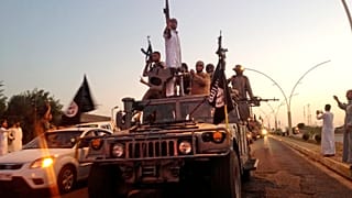 des combattants du groupe "État islamique" défilent à bord d'un véhicule blindé réquisitionné aux forces de sécurité irakiennes, à Mossoul, en Irak, le 23 juin 2014