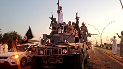 des combattants du groupe "État islamique" défilent à bord d'un véhicule blindé réquisitionné aux forces de sécurité irakiennes, à Mossoul, en Irak, le 23 juin 2014