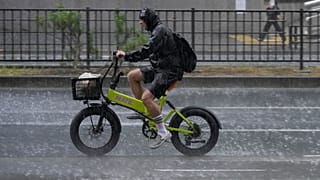 Un ciclista circula bajo una lluvia intensa y repentina en Tokio, el 13 de agosto de 2026.