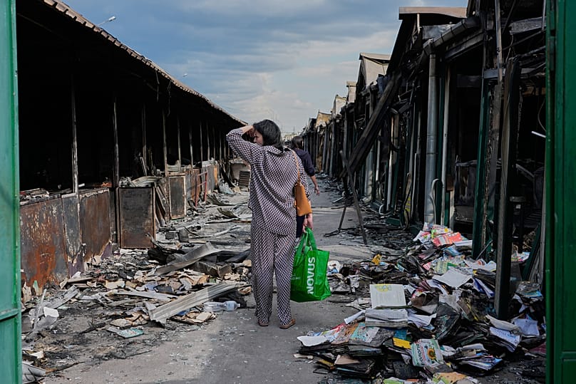 Mulher reage a livros carbonizados após um incêndio no maior mercado de livros do país, provocado por um ataque de míssil russo em Kiev, 19 de agosto de 2026