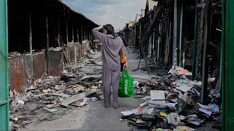 Eine Frau reagiert erschüttert auf verkohlte Bücher nach einem Brand auf dem größten Buchmarkt des Landes, ausgelöst durch einen russischen Raketenangriff in Kyjiw, 19. August 2026