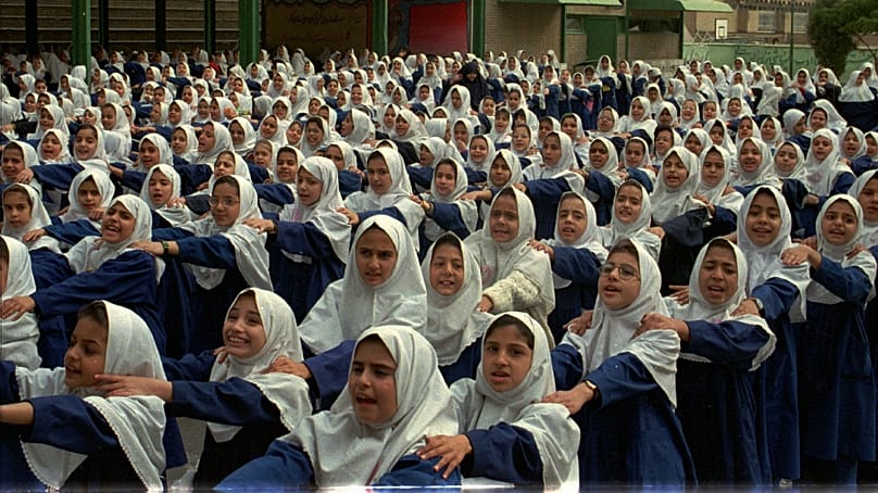 دانش‌آموزان دختر دبستانی ایرانی قبل از شروع کلاس‌ها در صف بیرون مدرسه ابتدایی خود در تهران، ایران، ۲۷ اکتبر ۱۹۹۷