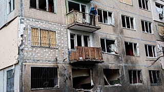 A man stands on a balcony of an apartment building damaged after a Russian drone strike in Kyiv, 22 September, 2026