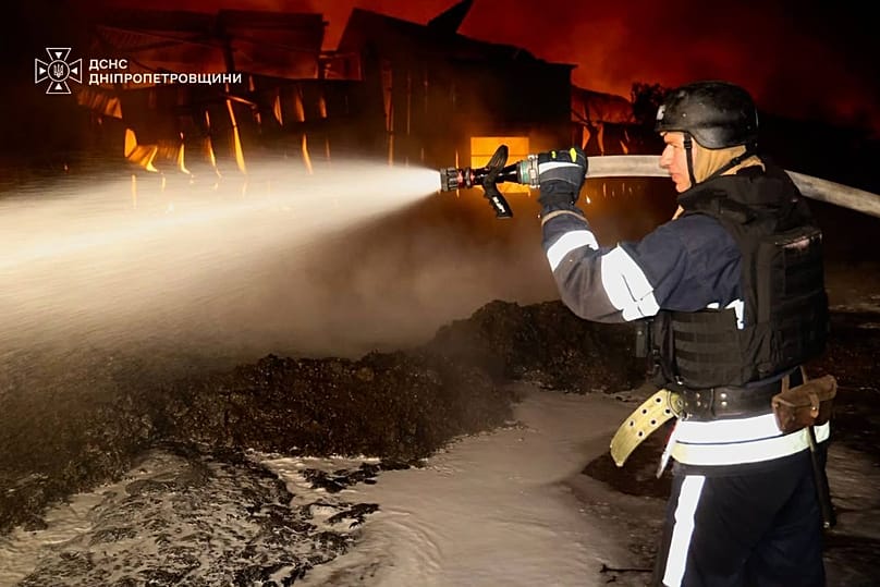 A rescue worker put out a fire of a infrastructure facility damaged after a Russian strike on Dnipropetrovsk region, 22 September, 2026