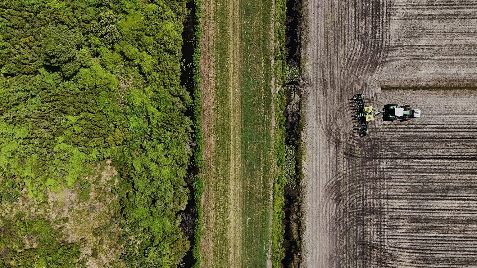 Luftaufnahme: Arbeiter pflügt mit Traktor ein Feld