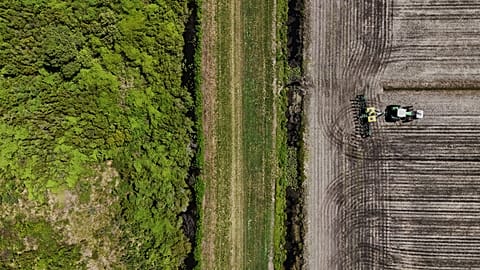 Aerial view of a worker ploughing the land with his tractor