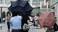A man with an umbrella struggles against strong wind brought by Typhoon Ampil, while walking on a street, in Tokyo, Japan, Friday, Aug. 16, 2024