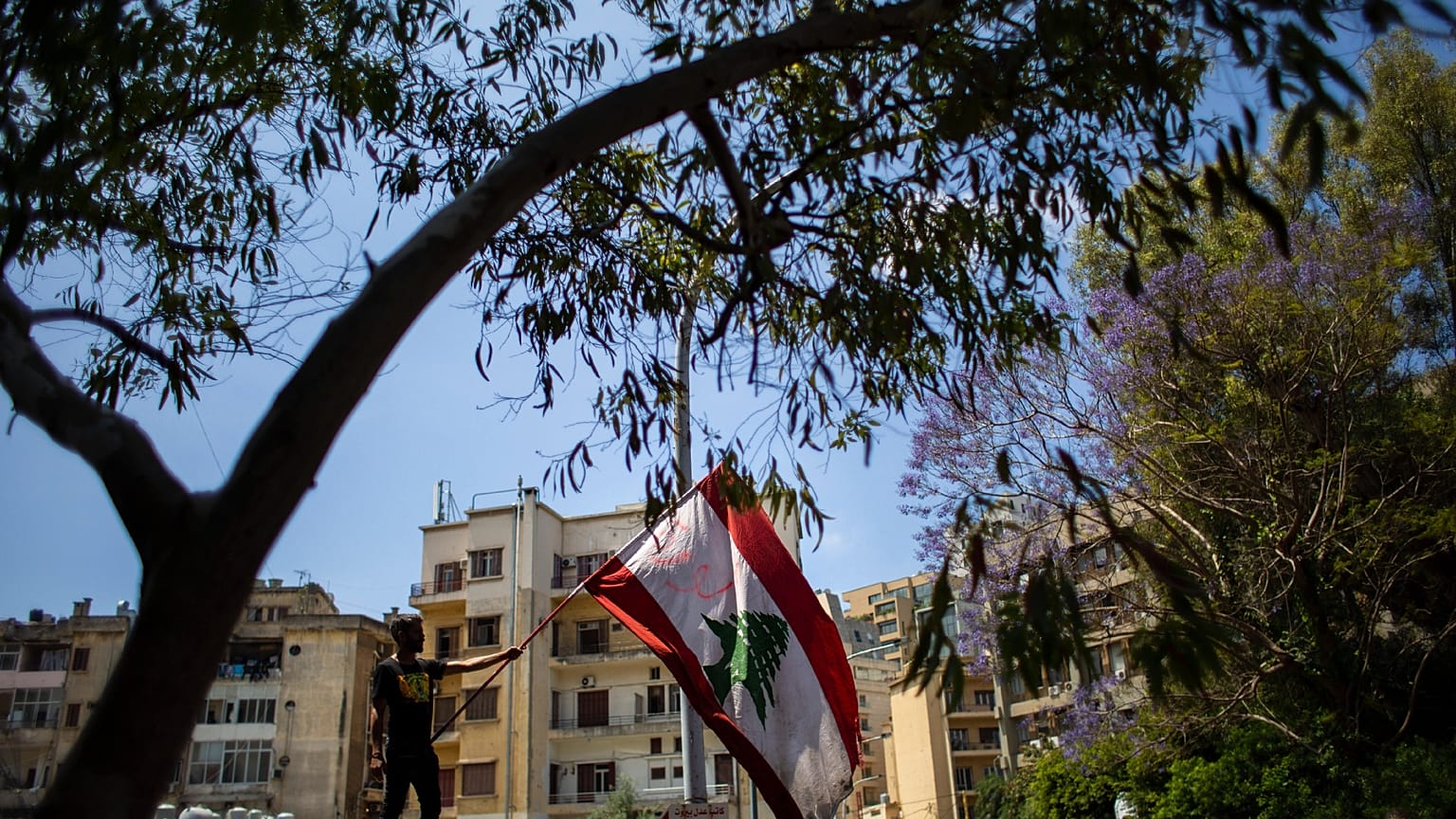 متظاهر مناهض للحكومة يلوح بالعلم اللبناني خلال الاحتجاجات المستمرة ضد الحكومة اللبنانية خارج قصر العدل في بيروت، لبنان، الخميس 7 مايو 2020.