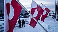 Women walk on a street in front of national flags in Nuuk, Greenland, Jan. 14, 2026.