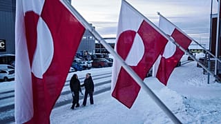 Women walk on a street in front of national flags in Nuuk, Greenland, Jan. 14, 2026.