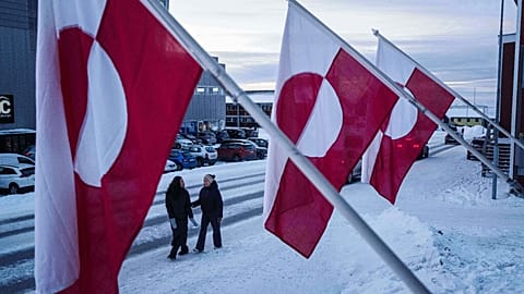 Women walk on a street in front of national flags in Nuuk, Greenland, Jan. 14, 2026.