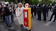 File - A protester carries a mock fuel pump during a May Day march in France on 1 May 2026, criticising fuel prices and oil companies. 