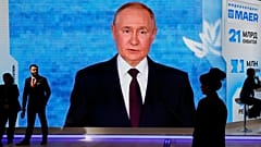 ARQUIVO: Pessoas passam diante de um ecrã com a imagem do presidente russo Vladimir Putin numa exposição no Fórum Económico Internacional de São Petersburgo, 4 de junho de 2026