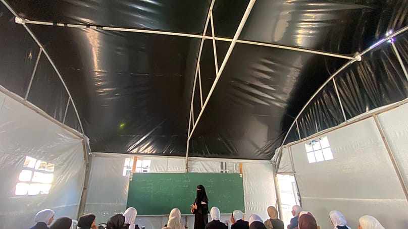 تلميذات يتابعن درسا داخل خيمة أقيمت فوق أنقاض مدرسة العروبة الثانوية التي دمّرها القصف الإسرائيلي، مخيم النصيرات، وسط قطاع غزة