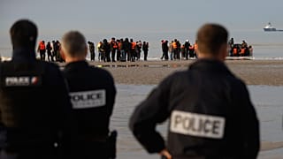 French police officers watch migrants returning to the beach after a failed attempt to reach Britain in Gravelines, 6 November, 2025