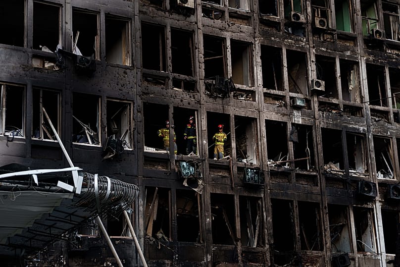 Rescuers look from the windows of an office building damaged by a Russian drone strike in Kyiv, 23 September, 2026