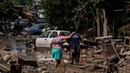 A Navy officer helps a woman cross a flooded street after heavy rain in Poza Rica, Veracruz state, Mexico, Oct. 12, 2025.