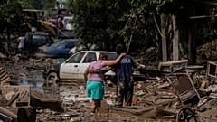 A Navy officer helps a woman cross a flooded street after heavy rain in Poza Rica, Veracruz state, Mexico, Oct. 12, 2025.