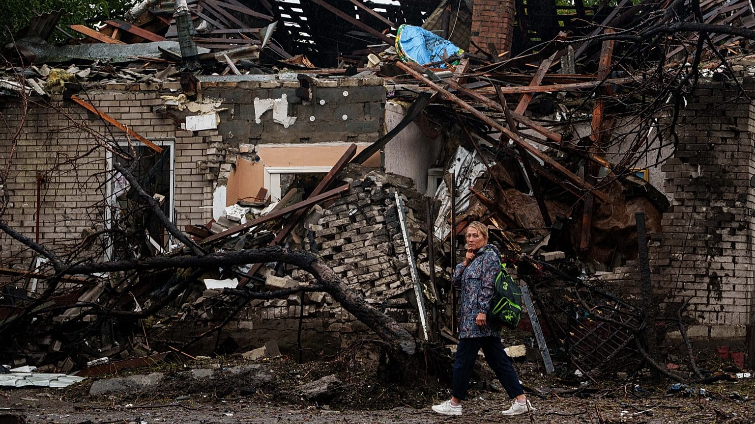 A woman walks in front of a house destroyed in a Russian strike on a residential neighbourhood in Kyiv, 24 September, 2026