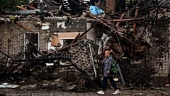 A woman walks in front of a house destroyed in a Russian strike on a residential neighbourhood in Kyiv, 24 September, 2026