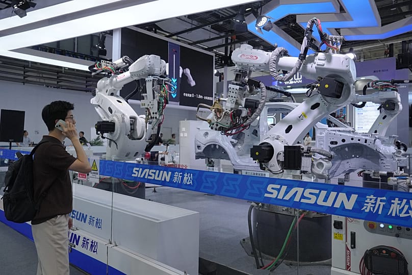 FILE. A visitor looks at robotic arms for industrial production at the World Robot Conference in Beijing, 19 Aug. 2026