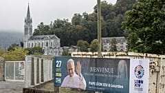A banner announces Pope Leo XIV's upcoming visit to Lourdes.