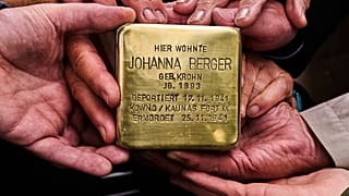 Verwandte halten den Stolperstein für Johanna Berger, die 1941 deportiert und ermordet wurde, vor deren früherem Wohnort in Berlin. 6. Mai 2026