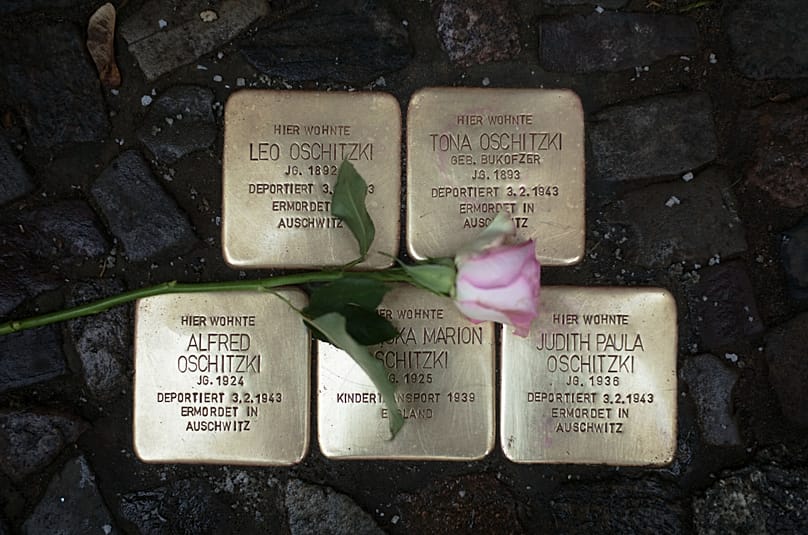 Vor einem Wohnhaus in Berlin liegt eine Blume auf polierten sogenannten „Stolpersteinen“, die an Menschen erinnern, die von den Nazis deportiert und ermordet wurden