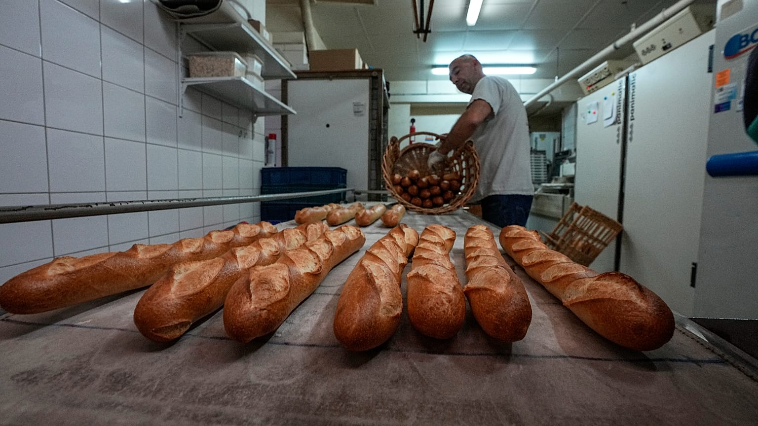Baker David Buelens puts the baguettes into a basket at a bakery, in Versailles, west of Paris