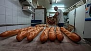 Baker David Buelens puts the baguettes into a basket at a bakery, in Versailles, west of Paris