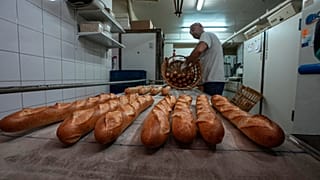 Baker David Buelens puts the baguettes into a basket at a bakery, in Versailles, west of Paris