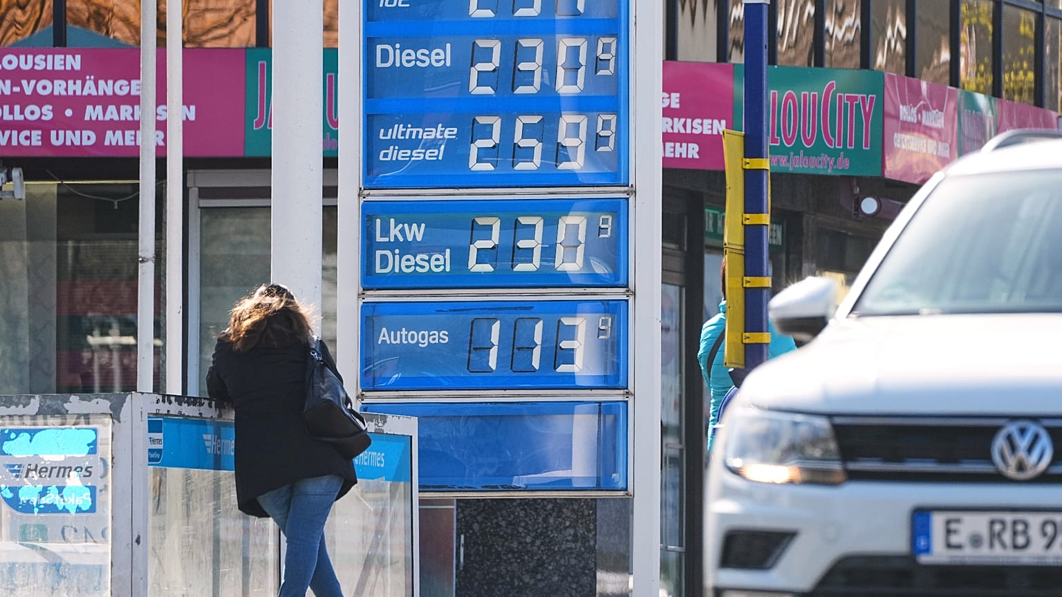 People wait for the bus at a fuel station in the City centre of Essen, Germany, that shows high fuel prices due to the war in Iran, Wednesday, April 1, 2026.