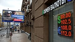 People walk past a currency exchange office with an army recruiting billboard calling for a contract for service in the Russian armed forces in Moscow, 14 August, 2023