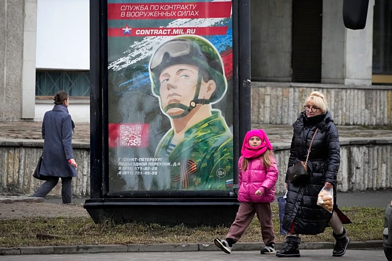 People walk past an army recruiting billboard in St. Petersburg, 24 March, 2023