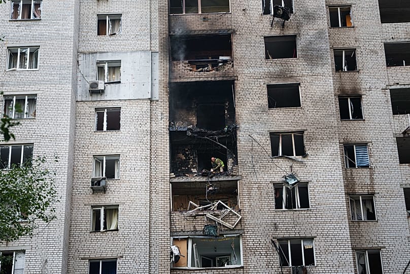 A police officer throws fragments of a Shahed drone from the balcony of a house damaged in a Russian strike on a residential neighbourhood in Kyiv, 25 September, 2026