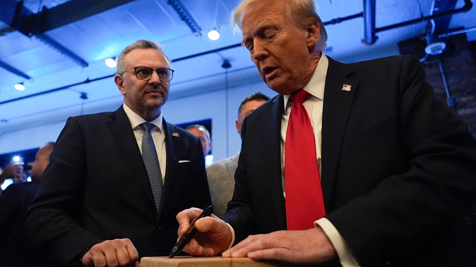 FILE - Republican presidential nominee former President Donald Trump signs autographs as Massad Boulos, watches as he visits The Great Commoner, Nov. 1, 2024, in Dearborn, Mi